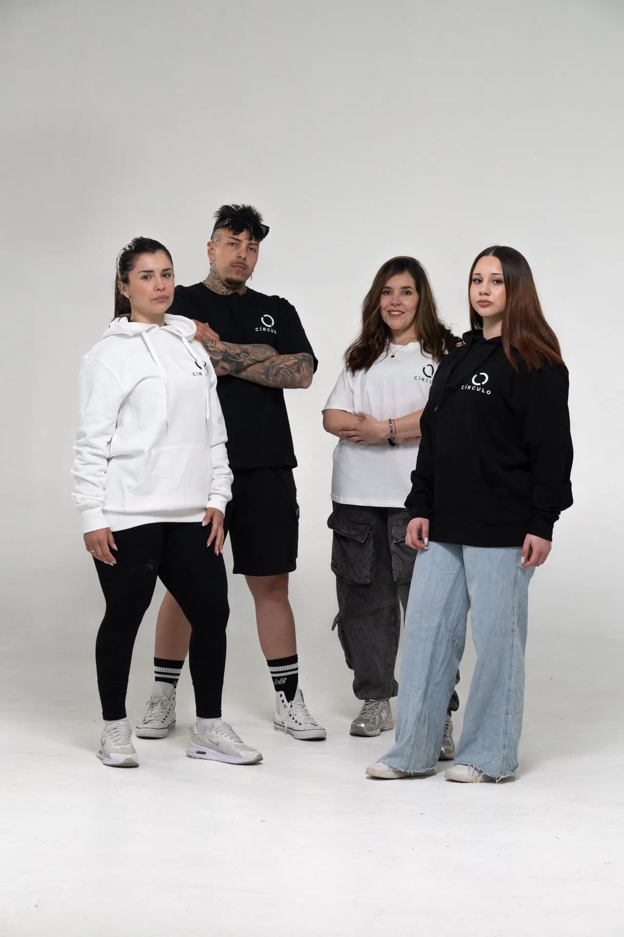 Cuatro personas con el canguro blanco, la remera negra, la remera blanca y el canguro negro del Drop 001